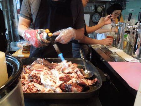 A cook heats pulled pork with a hand-held torch during a “pop-up” food event at Magpie Brewing Co. in Gyeongridan, Seoul, Saturday. / Korea Times photos by Kim Young-jin