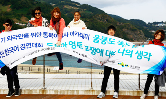 Foreign students from Mongolia, Ecuador, China and Singapore hold up a banner at Sadong Port on Ulleung Island, North Gyeongsang Province, Saturday, before embarking on a boat bound for Dokdo. The state-run Northeast Asian History Foundation arranged the field trip as part of its Northeast Asian history lectures for foreign students. / Korea Times photo by Yoon Sung-won