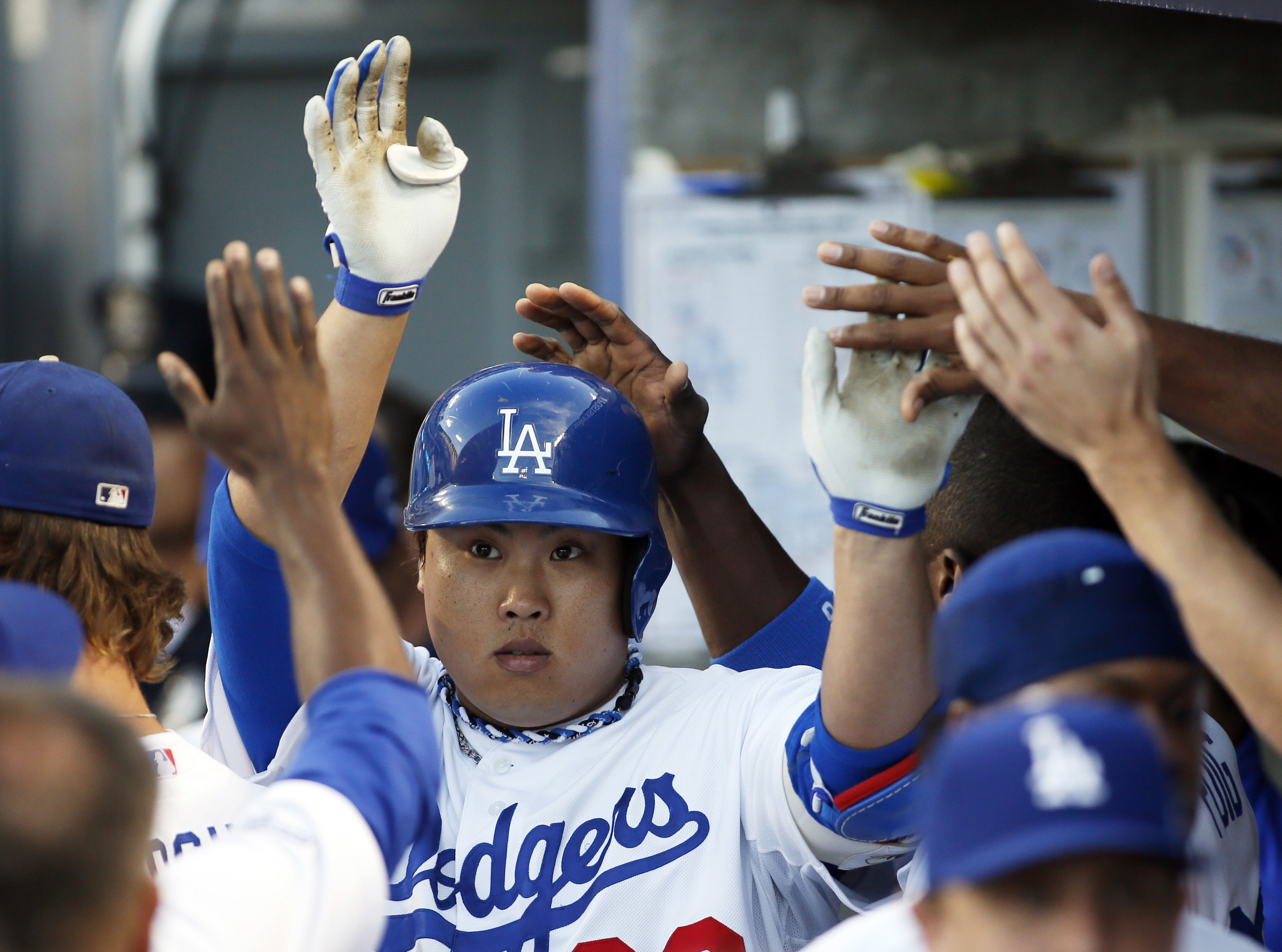 Los Angeles Dodgers starting pitcher Hyun-Jin Ryu high fives teammates in the dugout after he hit a sacrifice fly in the second inning of Game 3 of the National League division baseball series against the Atlanta Braves, Sunday, Oct. 6, 2013, in Los Angeles. (AP Photo/Danny Moloshok)
