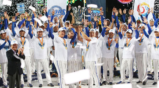 Samsung Lions players celebrate holding the trophy after beating the Doosan Bears 7-3 to capture the Korean Series in seven games at Daegu Stadium, Friday. They became the first team to claim three consecutive Korean Baseball Organization championships. / Yonhap