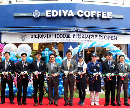Moon Chang-ki, center, CEO of Ediya Coffee, cuts the ribbon with company employees during an opening ceremony for Ediya’s 1,000th store in Dongdaemun-gu, Seoul, Oct. 29, 2013.