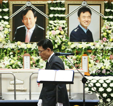 LG Electronics Vice President Nam Sang-geon walks past the photographs of the company’s two helicopter pilots — Park In-kyu and Koh Jong-jin — before making a address at their memorial service at Asan Medical Center in southern Seoul, Tuesday. The two pilots were killed during a flight from Gimpo International Airport to the Jamsil Heliport after their helicopter crashed into an I’Park apartment in Samseong-dong, southern Seoul, Saturday, in heavy fog. / Yonhap