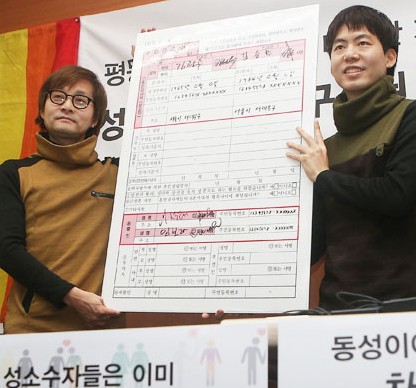 Movie director Kim-Jho Kwang-soo, left, 48, and his partner Kim Seung-hwan hold a blown-up copy of a marriage registration form during a press conference at which they urged the government to recognize their union at the office of the People’s Solidarity for Participatory Democracy in central Seoul, Tuesday. They sent their marriage registration form to Seodaemun District Office, but the office said it will not accept it. (Yonhap)