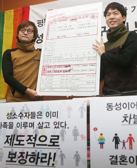 Movie director Kim-Jho Kwang-soo, left, 48, and his partner Kim Seung-hwan hold a blown-up copy of a marriage registration form during a press conference at which they urged the government to recognize their union at the office of the People’s Solidarity for Participatory Democracy in central Seoul, Tuesday. They sent their marriage registration form to Seodaemun District Office, but the office said it will not accept it. (Yonhap)