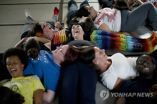 People laugh as they take part in performing a group exercise during a laughter yoga class in St. Albans, England on Sunday, June 9, 2013. (AP Photo/ yonhap)