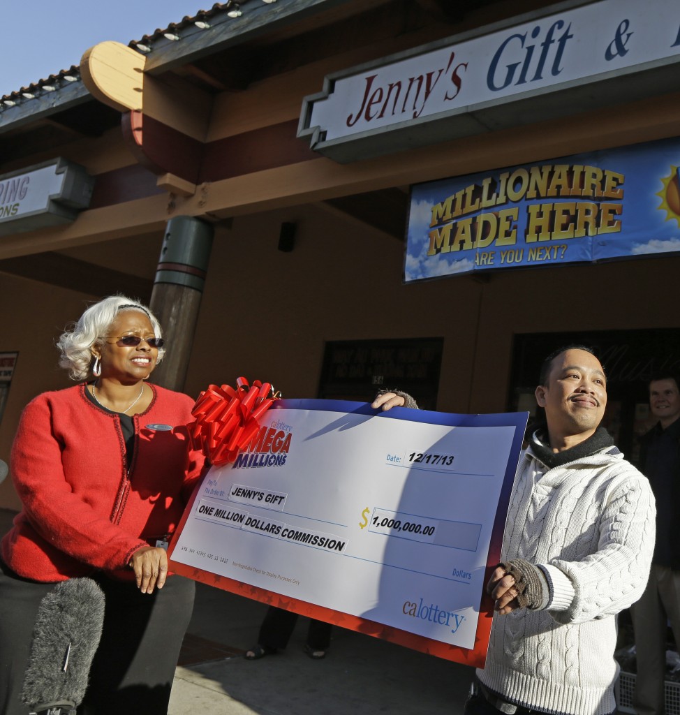Jenny's Gift Shop owner Thuy Nguyen, right, accepts a $1 million check from California lottery sales representative Mona Sanders Wednesday, Dec. 18, 2013, in San Jose, Calif. Two lucky winning tickets were sold in Tuesday's near-record $636 million Mega Millions drawing: one at a tiny newsstand in Atlanta, and the other more than 2,000 miles away in California. huy Nguyen, says he doesn't know who the bought the winning ticket, but it's likely someone he knows, as most of his customers are his friends. (AP Photo/Ben Margot)