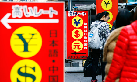 Tourists pass by a currency exchange signboard in the shopping district of Myeong-dong, downtown Seoul, Sunday. (Yonhap)