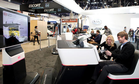 Visitors try out next-generation smart car technology at Kia Motors’ booth at the 2014 International Consumer Electronics Show at the Las Vegas Convention Center. (Courtesy of Kia Motors)