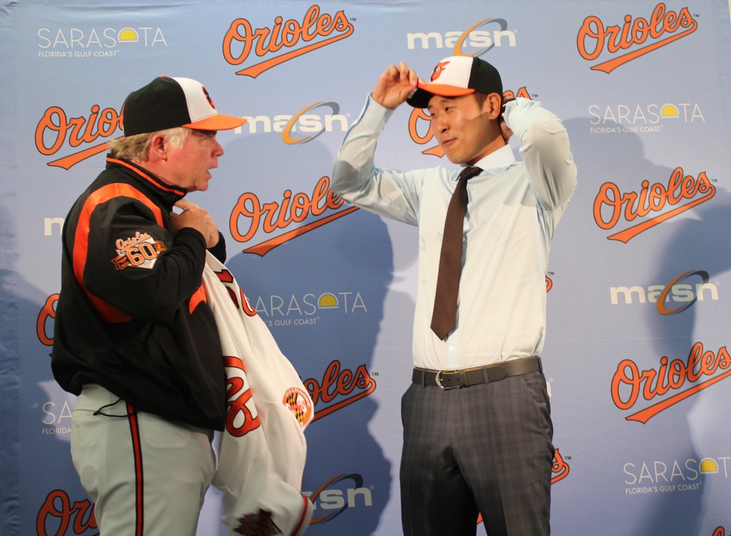 Korean pitcher Yoon Suk-min, right, puts on the Baltimore Orioles cap, while the Orioles manager Buck Showalter waits to help him put on his new uniform jersey. (Yonhap)