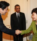 President Park Geun-hye and Japanese Prime Minister Shinzo Abe shake hands during a trilateral summit with President Barack Obama at the U.S. embassy in The Hague. (Yonhap)