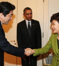President Park Geun-hye and Japanese Prime Minister Shinzo Abe shake hands during a trilateral summit with President Barack Obama at the U.S. embassy in The Hague. (Yonhap)
