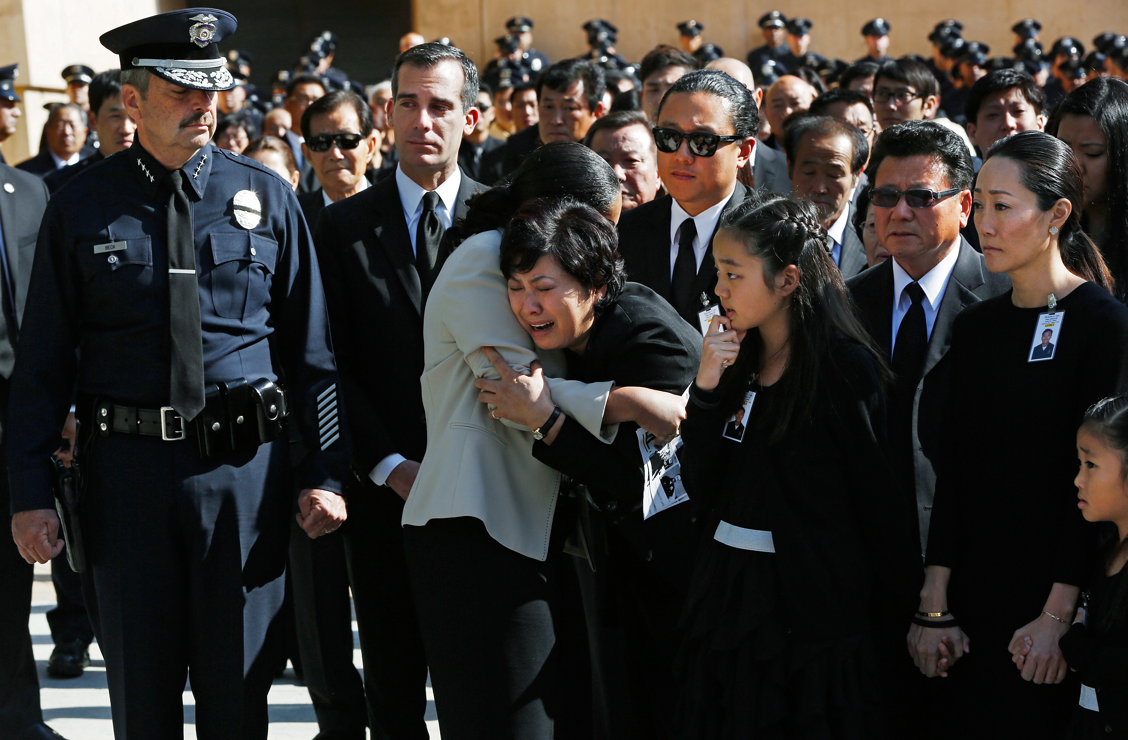 Choung Ja Lee, mother of fallen Los Angeles Police Department Nicholas Choung Lee, fourth from left, is helped by a LAPD female police officer, as her son's casket leaves a funeral mass at the Cathedral of Our Lady of the Angels in Los Angeles Thursday, March 13, 2014. Others from left include Los Angeles Police Chief Charlie Beck, Mayor Eric Garcetti, Lee's daughter Jalen, middle front, brother Danny, center rear, father Heung Jae Lee, and wife Cathy Kim, right.  Lee, 40, died when the squad car he and his partner were in collided with a trash truck in Beverly Hills on March 7. (AP Photo/Damian Dovarganes)