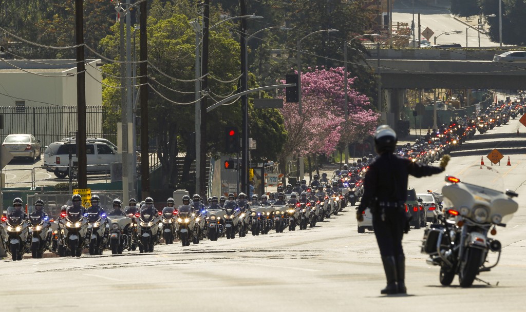 A motorcade of Los Angeles police officers escorts a hearst carrying the casket of fallen LAPD Officer Nicholas Choung Lee after his funeral mass at the Cathedral of Our Lady of the Angels in Los Angeles, Thursday, March 13, 2014. Lee, 40, died when the squad car he and his partner were in collided with a trash truck in Beverly Hills on March 7. (AP Photo/Damian Dovarganes)