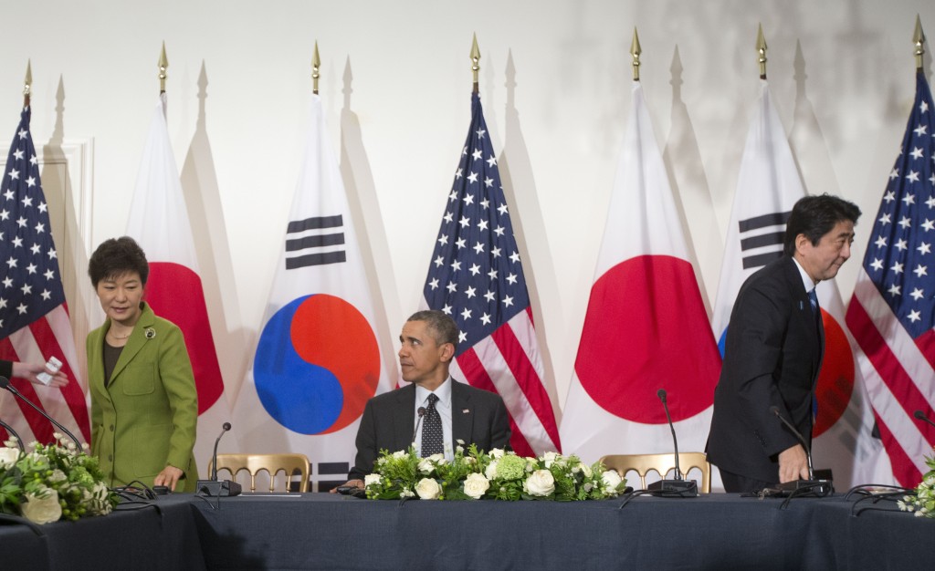 President Barack Obama watches as South Korean President Park Geun-hye, left, and Japanese Prime Minister Shinzo Abe, leave their seats at the opposite ends of the table, Tuesday, March 25, 2014, during the start of their trilateral meeting at the US Ambassador's Residence in the Hague, Netherlands. (AP Photo/Pablo Martinez Monsivais)