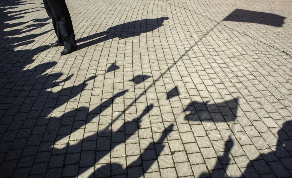 FILE - In this Tuesday, March 18, 2014 file photo people cast shadows waving flags as they gather at a square to watch a televised address by Russian President Vladimir Putin to the Federation Council, in Sevastopol, Crimea. Now, waking in a land officially annexed by Russia, the Crimean Tatars are worried about what is to come. They worry about how Russian neighbors will behave. Nonetheless, most of them have decided to stay. People from other ethnic groups are staying for several reasons. First among them is economic. Many fear leaving their homes behind, or being robbed as they flee. And some families simply have nowhere to go. (AP Photo/Andrew Lubimov, File)