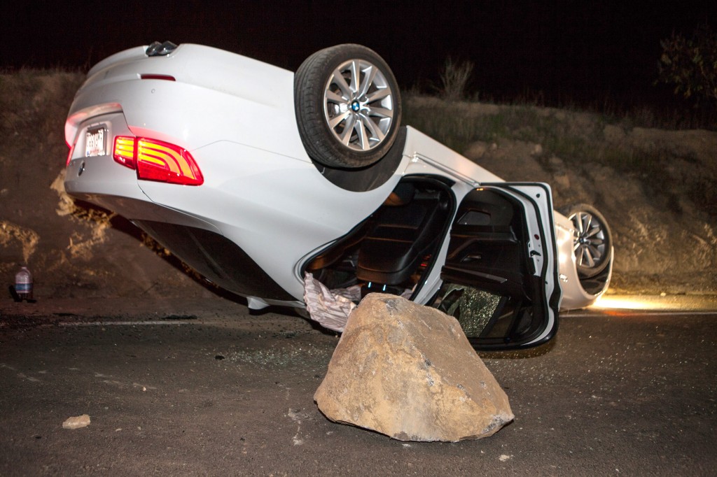 A car sits overturned on a highway in the Carbon Canyon area of Brea, Calif., Friday night, March 28, 2014, after hitting a rock slide caused by an earthquake. The people inside the car sustained minor injuries. A magnitude-5.1 earthquake centered in the area near Los Angeles caused no major damage but jittered nerves throughout the region as dozens of aftershocks struck into the night. (AP Photo/Kevin Warn)