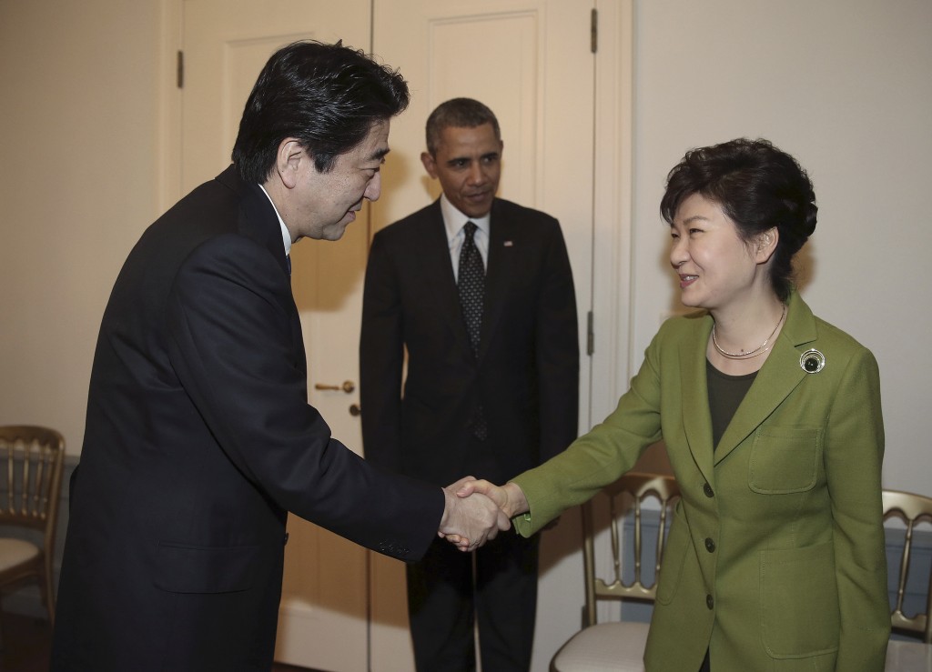 South Korean President Park Geun-hye, right, shakes hands with Japanese Prime Minister Shinzo Abe, left, as US President Barack Obama looks on before their trilateral meeting at the US Ambassador's Residence in the Hague, Netherlands, Tuesday, March 25, 2014. (AP Photo/Yonhap, Do Kwang-hwan)   