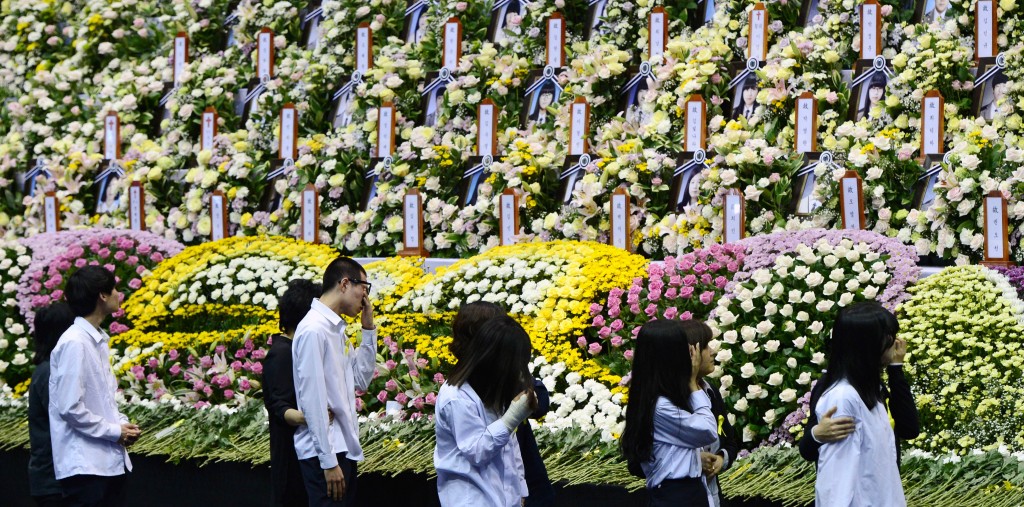 Danwon High School students rescued from the sunken ferry Sewol are overwhelmed with emotion while passing an array of photographs of their fellow students who didn’t survive during their trip to a joint memorial altar set up in Ansan Hwarang Park, Gyeonggi Province, Wednesday. (Yonhap)