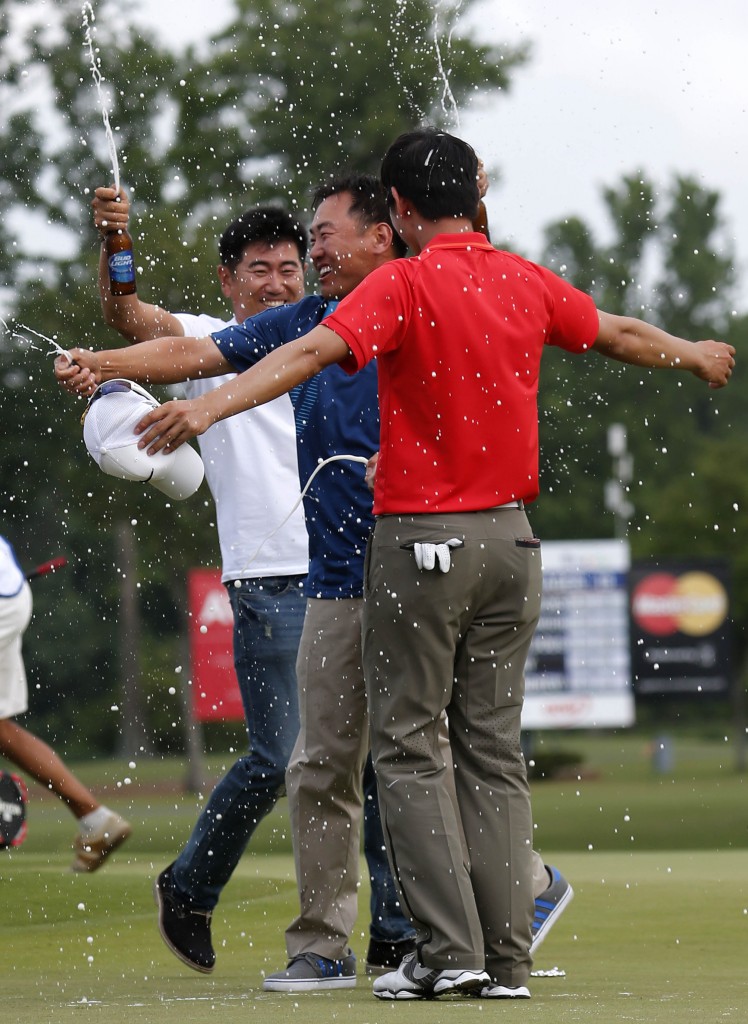 South Korean golfers Y.E. Yang, left, and Charlie Wi, center, douse Noh Seung-yul, right, with beer on the 18th green after Noh won the Zurich Classic golf tournament at TPC Louisiana in Avondale, La., Sunday, April 27, 2014.(AP Photo/Bill Haber)