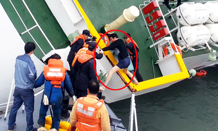 Sewol Captain Lee Joon-seok in his underwear is being rescued from the ship as it capsizes by first responders in this still from a video capturing the sinking of the ferry on April 16, which was released by the Coast Guard, Monday. While Lee and other crewmembers were taking flight, other footage shows few people on the decks, with hundreds of students heeding the crew’s instructions and staying inside their cabins. Over 300 people, mostly students on a school trip, have been confirmed dead or listed as missing. / Yonhap