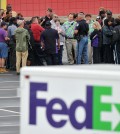A Cobb County Police Officer speaks to FedEx employees and family members gathered at the parking lot of a skating rink located near the shipping facility where a gunman open fire in Kennesaw, Ga., on Tuesday, April 29, 2014.  A shooter described as being armed with an assault rifle and having bullets strapped across his chest "like Rambo" opened fire Tuesday morning at a FedEx station outside Atlanta, wounding at least six people before police found the suspect dead from an apparent self-inflicted gunshot.  (AP Photo/Atlanta Journal-Constitution, Brant Sanderlin)