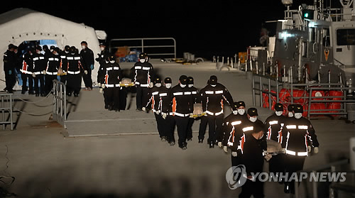Workers carry dead bodies found inside the ship Monday. / Yonhap