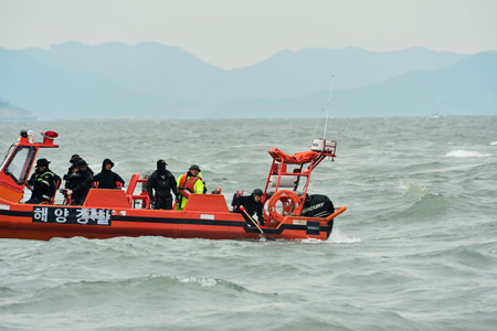 A group of Coast Guard officers on a boat pull an unidentified object from the waters, Saturday, near the site where the ferry Sewol sank in a deadly accident in waters off the southwestern coast. As of 0:30 a.m., Sunday, (Korea Times photo by Shim Hyun-chul)
