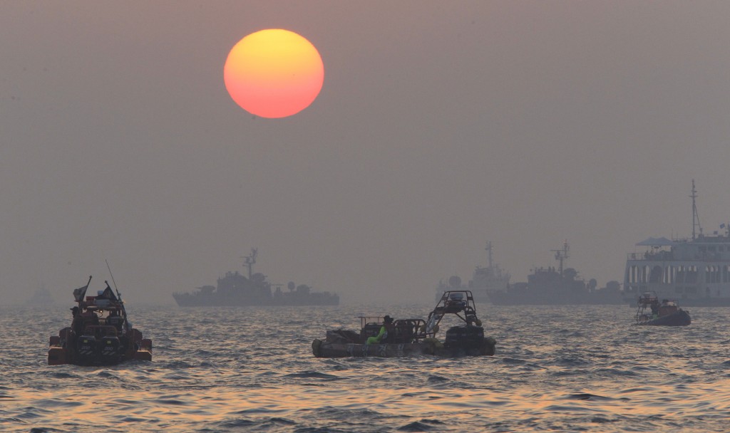 Searchers and divers look for people believed to have been trapped in the sunken ferry Sewol near buoys which were installed to mark the vessel in the water off the southern coast near Jindo, south of Seoul, South Korea, Tuesday, April 22, 2014. One by one, coast guard officers carried the newly arrived bodies covered in white sheets from a boat to a tent on the dock of this island, the first step in identifying a sharply rising number of corpses from the South Korean ferry that sank nearly a week ago. (AP Photo/Ahn Young-joon)