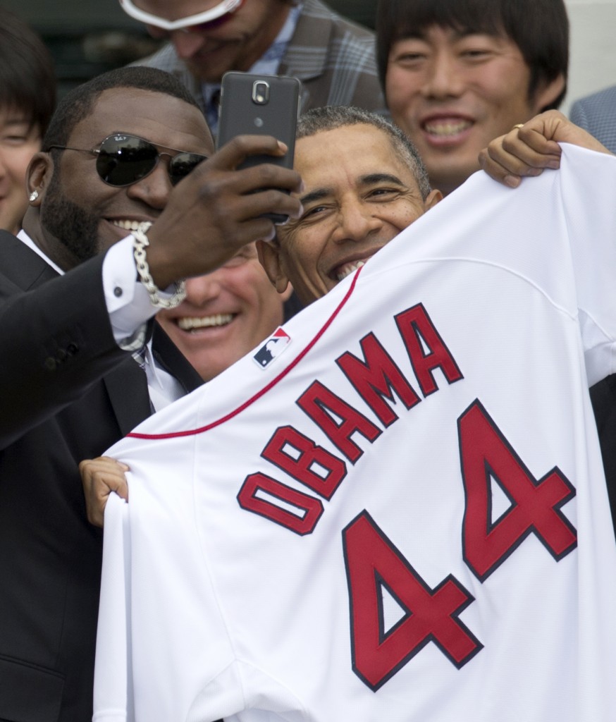 In this Tuesday, April 1, 2014, file photo, Boston Red Sox designated hitter David "Big Papi" Ortiz takes a selfie with President Barack Obama, holding a Boston Red Sox jersey presented to him, during a ceremony on the South Lawn of the White House in Washington, where the president honored the 2013 World Series baseball champion Boston Red Sox. Ortiz tweeted the selfie to his followers Tuesday, and it was resent by tens of thousands, including Samsung, which retweeted it as an ad. The White House press secretary says Obama was not aware that the photo was part of a marketing stunt. (AP Photo/Carolyn Kaster, File)