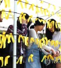 Students at Joongbu University tie yellow ribbons written with messages of hope on April 23. / Yonhap