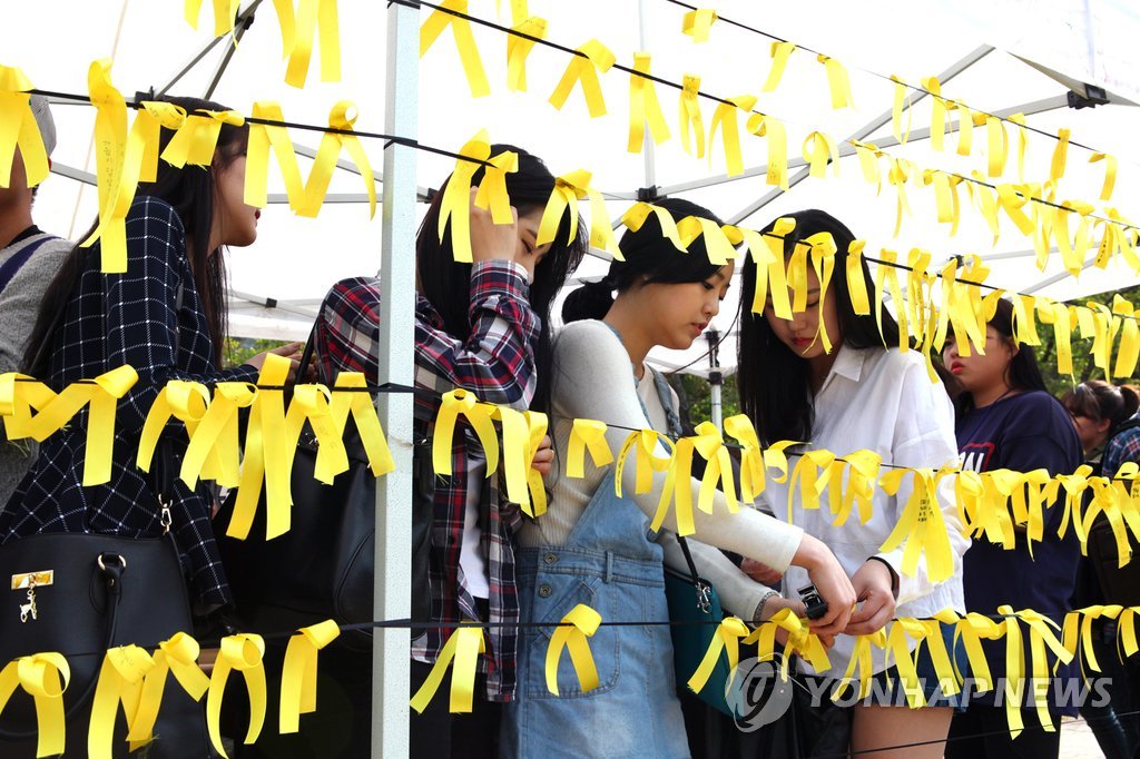 Students at Joongbu University tie yellow ribbons written with messages of hope on April 23. / Yonhap