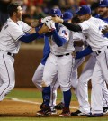 Texas Rangers' Shin-Soo Choo, center, is swarmed by teammates including J.P. Arencibia, left, and Martin Perez, right, after drawing a bases-loaded game-winning walk in a baseball game against the Philadelphia Phillies, Wednesday, April 2, 2014, in Arlington, Texas. The Rangers won 4-3. (AP Photo/Jim Cowsert)