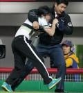 A fan is being forced out of Gwangju-Kia Champions Field on April 30, 2014, after attacking an umpire during a game between the home team Kia Tigers and the visiting SK Wyverns. (Yonhap)