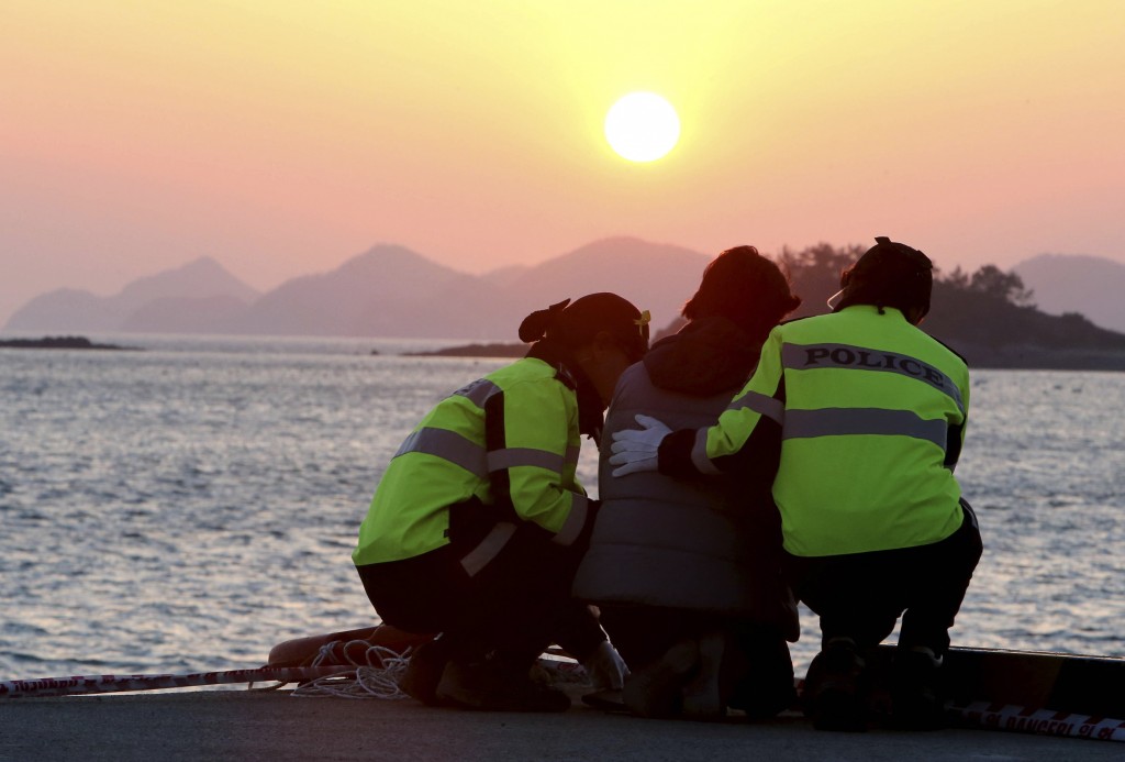 A relative, center, of a passenger aboard the sunken Sewol ferry is consoled by police officers as she awaits news on her missing loved one at a port in Jindo, South Korea, Wednesday, April 30, 2014.  (Yonhap)