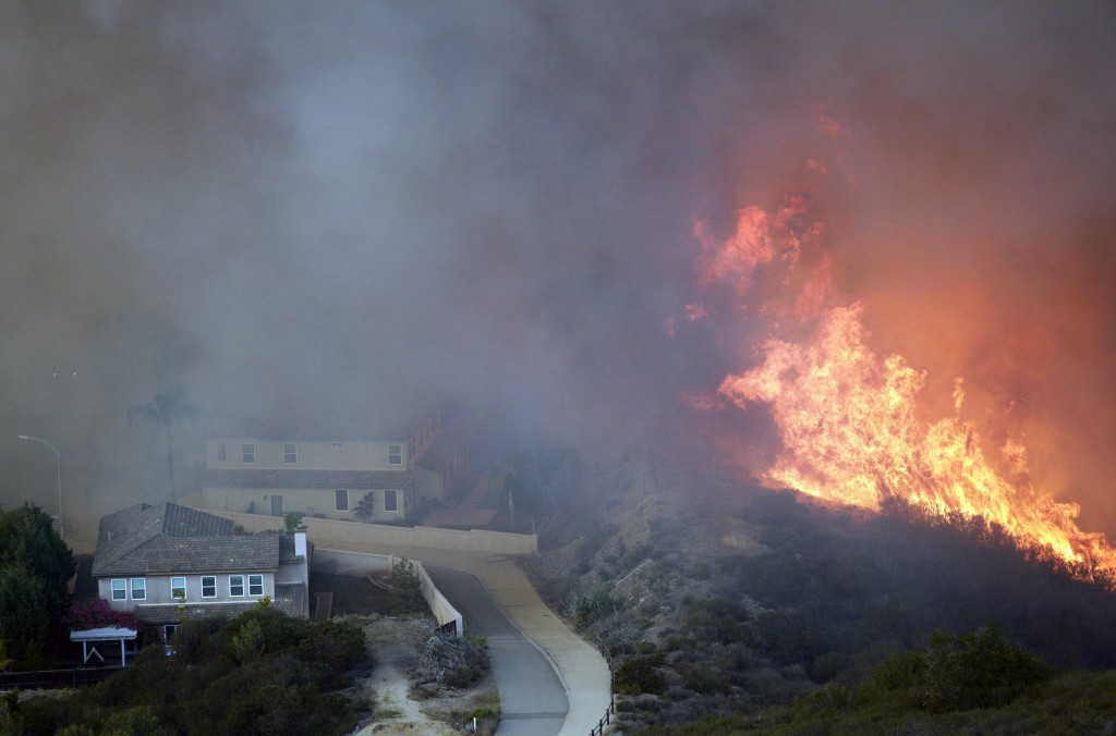 A wildfire approaches homes on Wednesday, May 14, 2014, in San Marcos, Calif. Flames engulfed suburban homes and shot up along canyon ridges in one of the worst of several blazes that broke out Wednesday in Southern California during a second day of a sweltering heat wave, taxing fire crews who fear the scattered fires mark only the beginning of a long wildfire season. (AP Photo/)