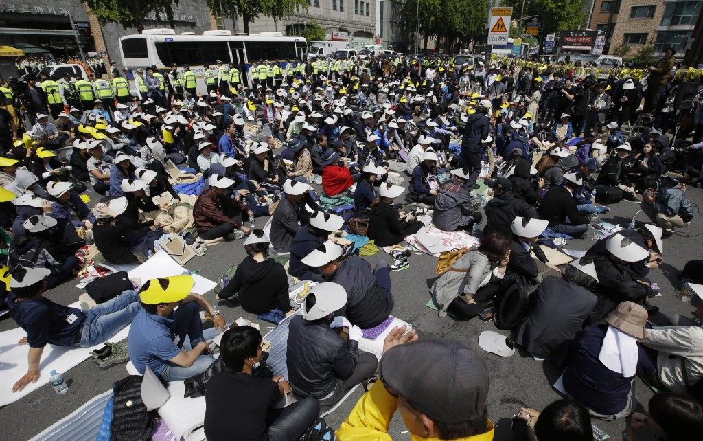 Family members of the victims of the sunken ferry Sewol and citizens sit on the street near the presidential Blue House in Seoul, South Korea, Friday, May 9, 2014. Family members marched to the presidential Blue House in Seoul early Friday calling for a meeting with President Park Geun-hye but ended up sitting on streets near the presidential palace after police officers blocked them. Park's office said a senior presidential official plans to meet them later Friday. (AP Photo/Lee Jin-man)