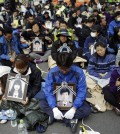 Family members holding the portraits of the victims of the sunken ferry Sewol, sit on the street near the presidential Blue House in Seoul, South Korea, Friday, May 9, 2014.