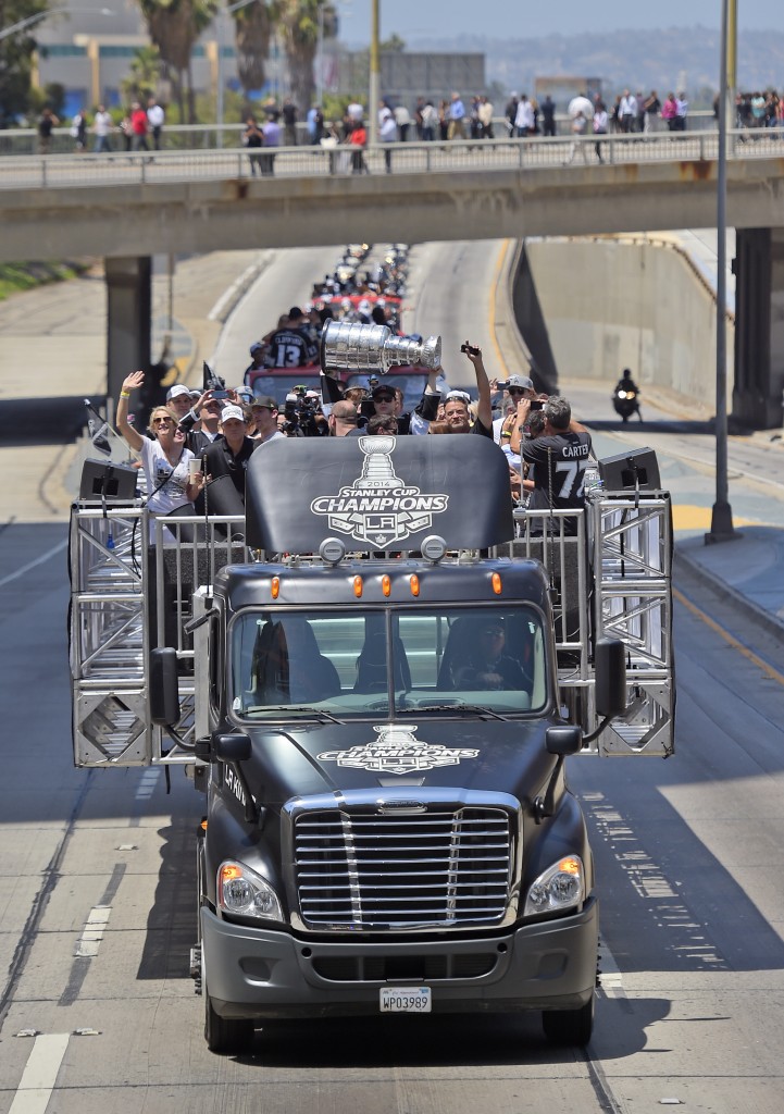 Dustin Brown of the Los Angeles Kings, holds up the Stanley Cup trophy while riding in a parade on the 110 freeway in downtown Los Angeles, Monday, June 16, 2014. The parade and rally were held to celebrate the Los Angeles Kings' second Stanley Cup championship in three seasons. (AP Photo/Mark J. Terrill)