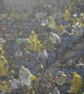 Spectators sit under pouring rain as they watch the group A World Cup soccer match between Mexico and Cameroon in the Arena das Dunas in Natal, Brazil, Friday, June 13, 2014.  (AP Photo/Hassan Ammar)