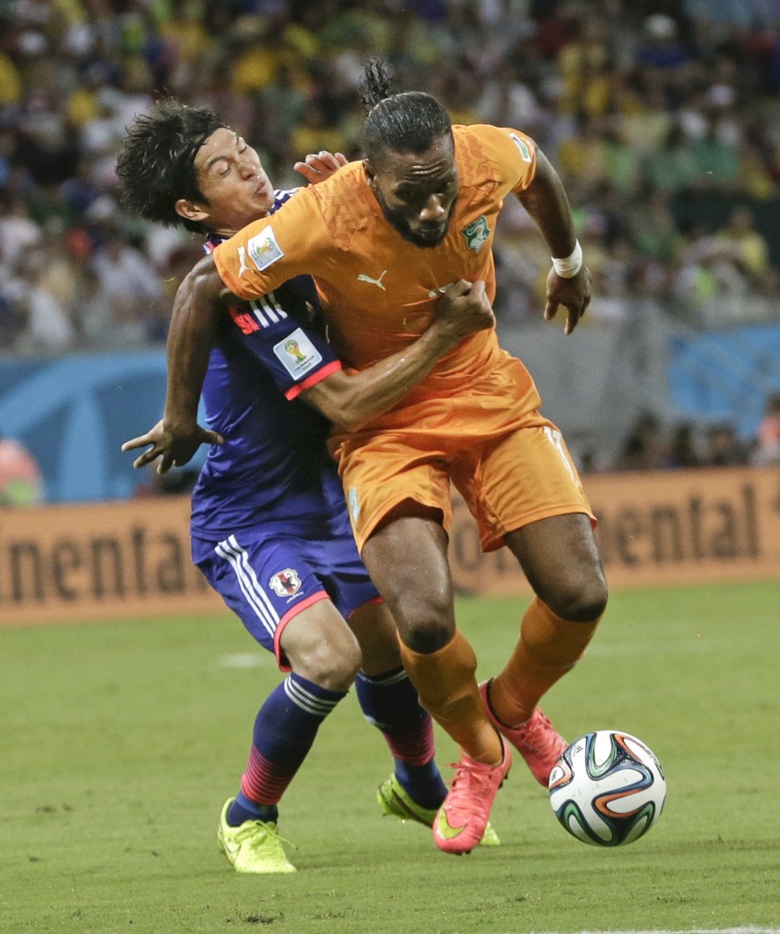 Japan's Masato Morishige, left, tries to hold Ivory Coast's Didier Drogba, right, during the group C World Cup soccer match at the Arena Pernambuco in Recife, Brazil, Saturday, June 14, 2014. (AP Photo/Petr David Josek)
