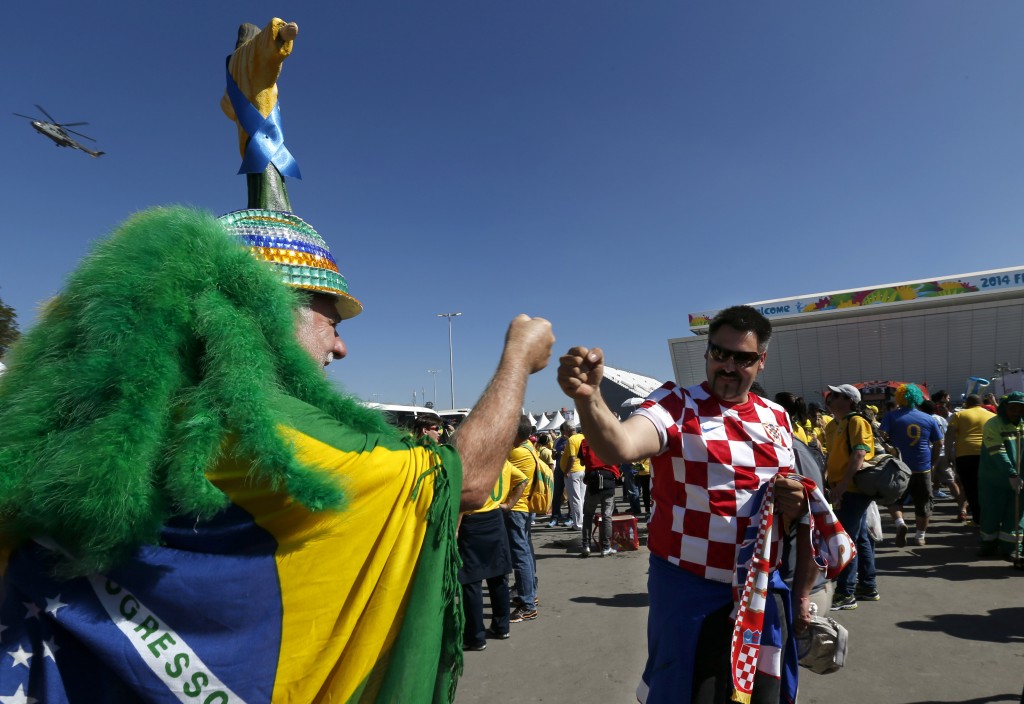 Brazilian soccer fan Amaceo Jgussi, left, fist bumps with Croatian fan Robert Krnezic, as they wait to enter the Itaquerao Stadium to watch the World Cup opening match, between Brazil and Croatia of group A, in Sao Paulo, Brazil, Thursday, June 12, 2014. Thursday is a holiday in Sao Paulo and everybody is celebrating the start of the international soccer tournament. Fans dressed in yellow and green greeted each other, often yelling, "Vai Brazil!" (AP Photo/Julio Cortez)