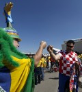 Brazilian soccer fan Amaceo Jgussi, left, fist bumps with Croatian fan Robert Krnezic, as they wait to enter the Itaquerao Stadium to watch the World Cup opening match, between Brazil and Croatia of group A, in Sao Paulo, Brazil, Thursday, June 12, 2014. Thursday is a holiday in Sao Paulo and everybody is celebrating the start of the international soccer tournament. Fans dressed in yellow and green greeted each other, often yelling, "Vai Brazil!"  (AP Photo/Julio Cortez)