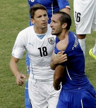 Italy's Giorgio Chiellini, right, shows his shoulder after colliding with Uruguay's Luis Suarez's mouth as Uruguay's Gaston Ramirez (18) watches during the group D World Cup soccer match between Italy and Uruguay at the Arena das Dunas in Natal, Brazil, Tuesday, June 24, 2014. (AP Photo/Hassan Ammar)