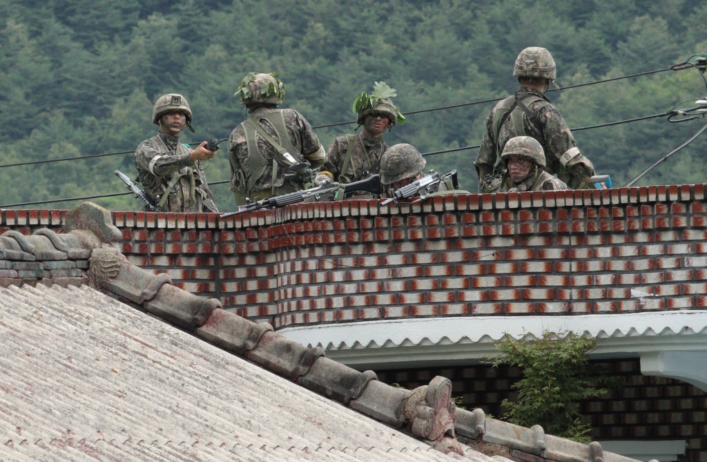 South Korean army soldiers take position on the roof of a private house to search for a South Korean conscript soldier who is on the run after a shooting incident in Goseong, South Korea, Sunday, June 22, 2014.  The military searched Sunday for an armed South Korean soldier who fled after killing five of his comrades and wounding seven at an outpost near the North Korean border. (AP Photo/Ahn Young-joon)