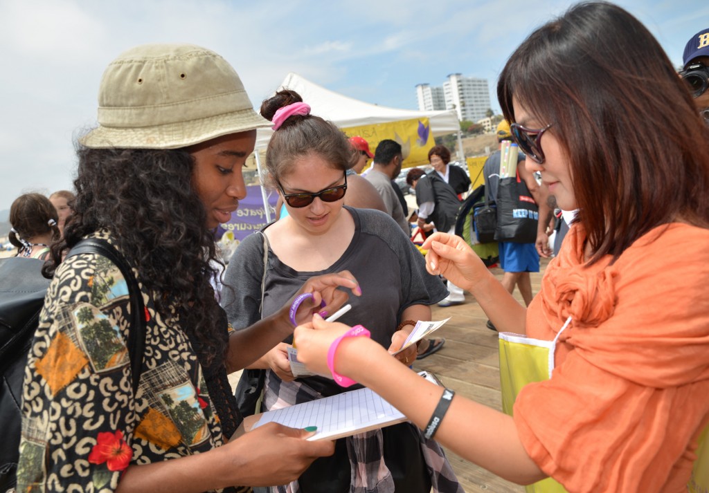 A Nabi USA member collects signatures from passerby at Santa Monica Pier for the 100 Million Signatures Campaign on June 21. (Kim Young-jae / The Korea Times)