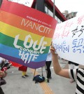 A woman, right, holds up a sign that reads, "Both parents are men, both parents are women. Our children are crying," beside an event supporter at the annual Korea Queer Festival (KQF) last week in Sinchon, northwestern Seoul. (Yonhap)