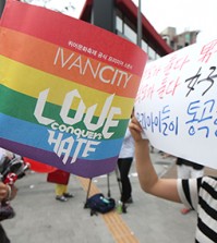 A woman, right, holds up a sign that reads, "Both parents are men, both parents are women. Our children are crying," beside an event supporter at the annual Korea Queer Festival (KQF) last week in Sinchon, northwestern Seoul. (Yonhap)