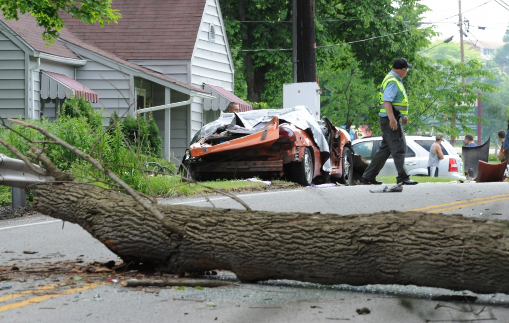 Conemaugh Township Police Chief Louis "Pete" Barclay surveys the scene of a double fatality caused by a large dead tree that fell directly onto a car carrying two adults (one pregnant) and four children on SR403 near Tire Hill, PA., Mon., June 23, 2014.  In Canada last Tuesday, a Korean couple from Baltimore also got killed when a storm caused a tree to fall on their car.  (AP )Photo/Tribune-Democrat, John Rucosky).