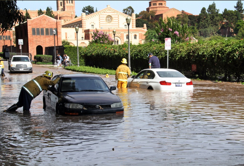 Los Angeles firefighters help drivers whose cars became stranded on Sunset Boulevard after a 30-inch water main broke and sent water flooding down Sunset and onto the UCLA campus, background, in the Westwood section of Los Angeles on Tuesday, July 29, 2014.(AP Photo/Steve Gentry)