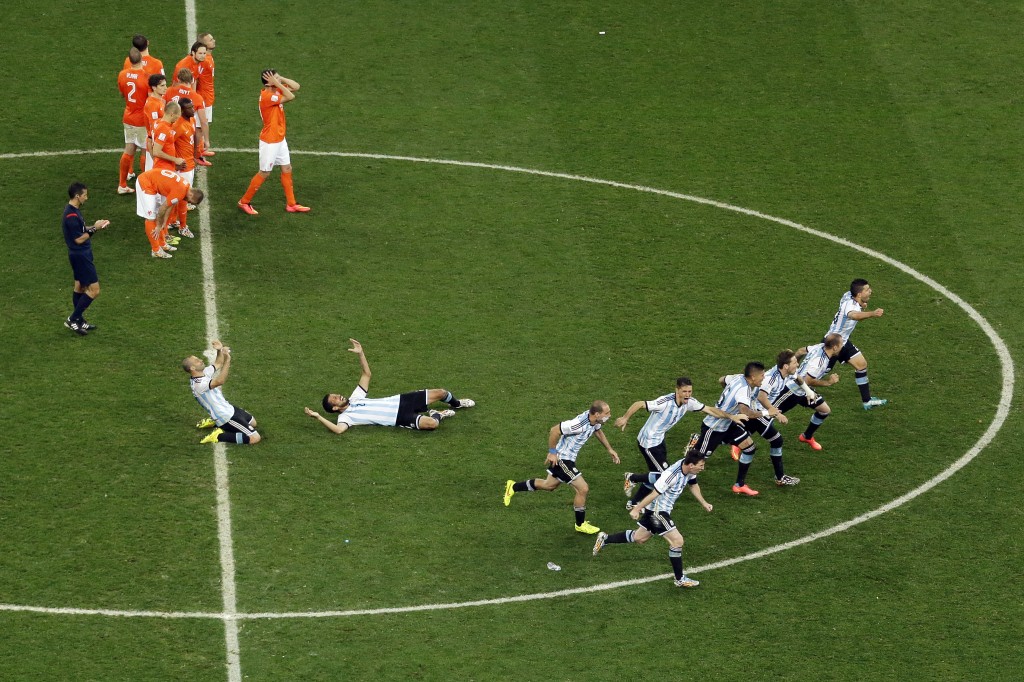 Argentina's players run to celebrate after teammate Maxi Rodriguez scored the last penalty as Netherlands' players react at the end of  the World Cup semifinal soccer match between the Netherlands and Argentina at the Itaquerao Stadium in Sao Paulo Brazil, Wednesday, July 9, 2014. Argentina reached the World Cup final on Wednesday after beating the Netherlands 4-2 in a penalty shootout.(AP Photo/Hassan Ammar)